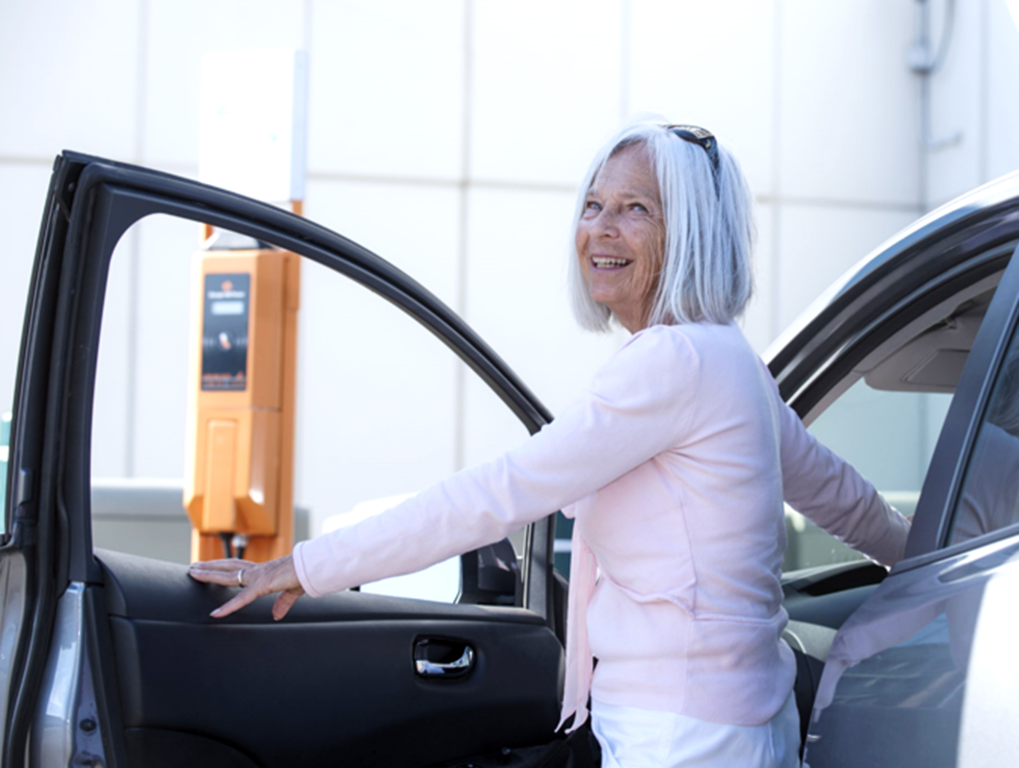 Une retraitée sort de sa voiture près d’une borne de recharge